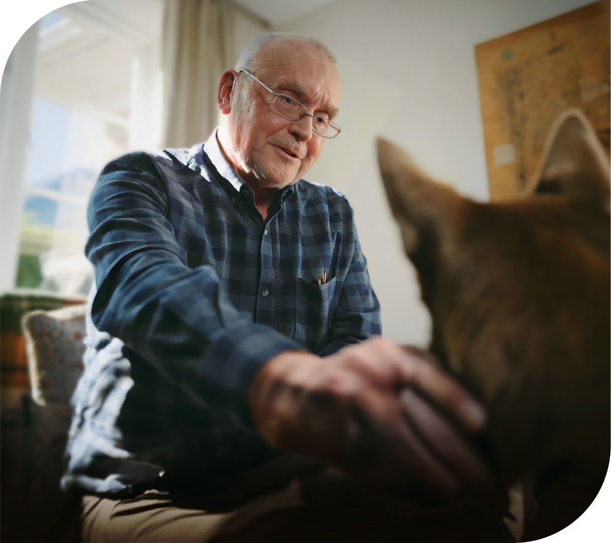 A man in his lounge chair scratches his dog behind the ear.