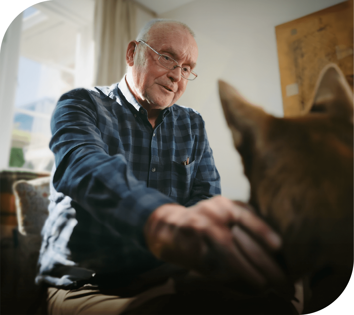 A man in his lounge chair scratches his dog behind the ear.