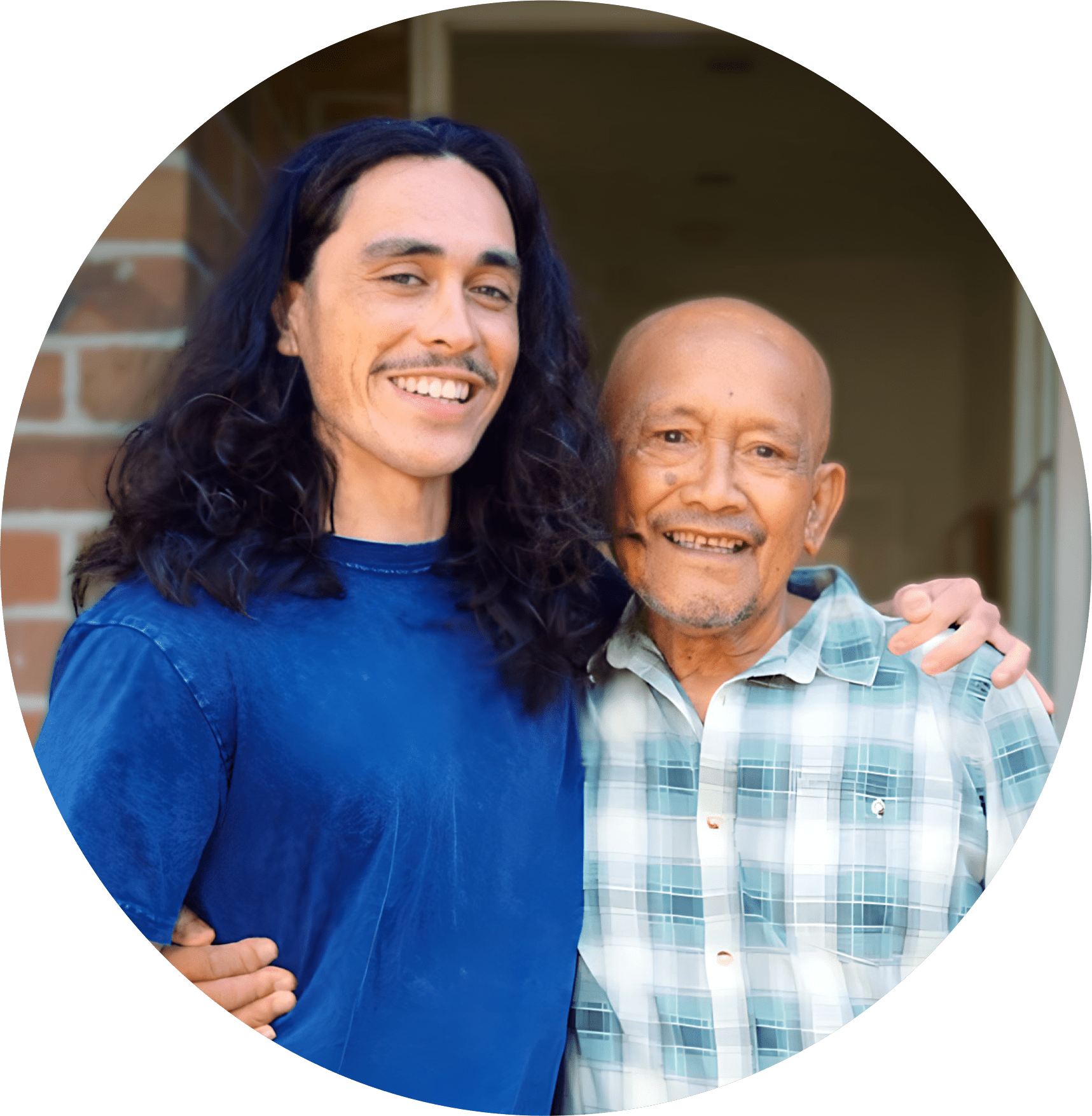 A young 20 something man proudly stands with his arm around his granddad.